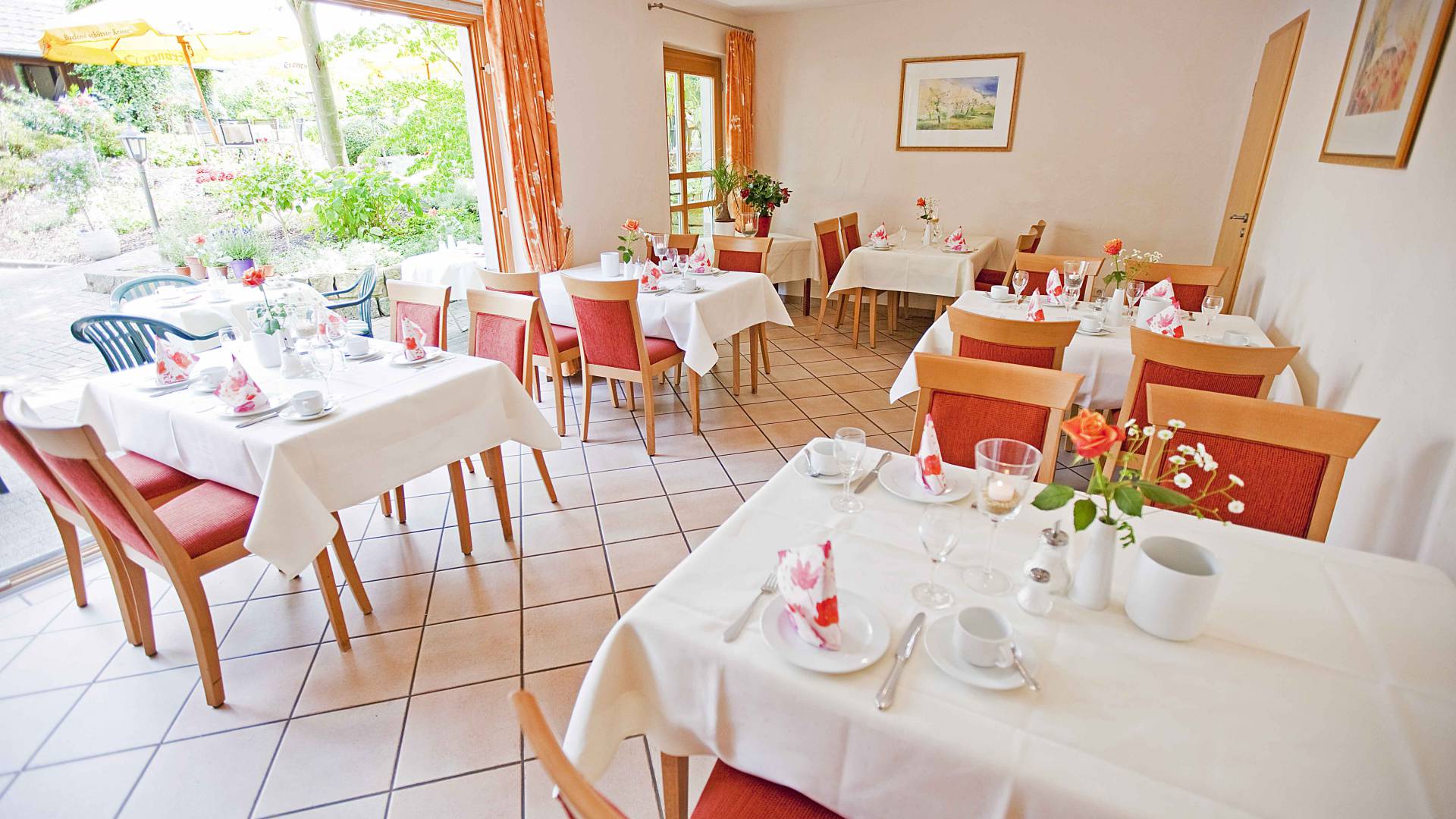 Innenansicht Gaststube mit gedeckten Tischen und Blick in den Garten